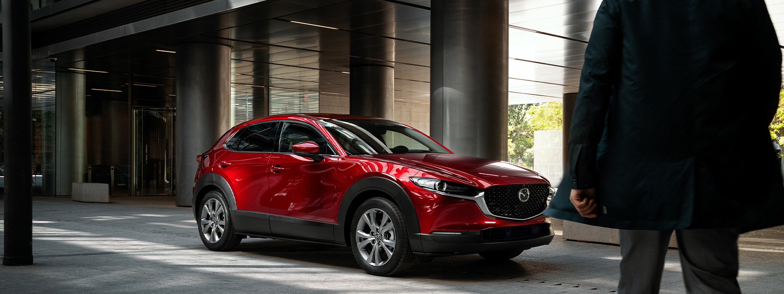 Une Mazda rouge stationnée devant des colonnes grises