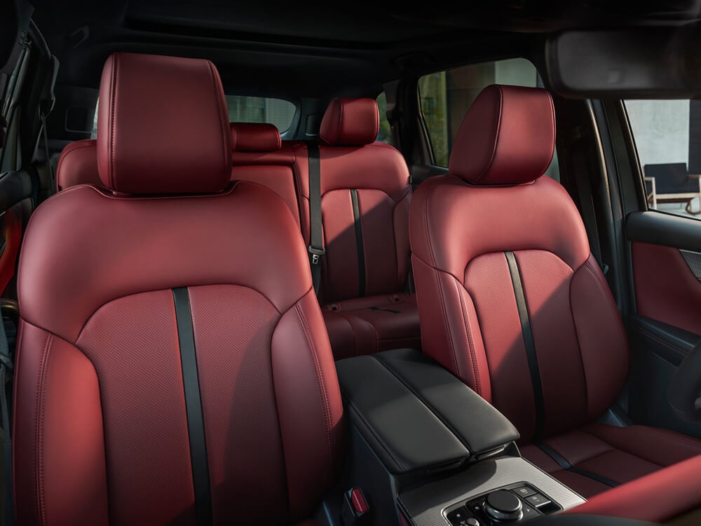 Vue d’ensemble des sièges avant et de la deuxième rangée en cuir rouge grenat à l’intérieur d’un Mazda CX-70.
