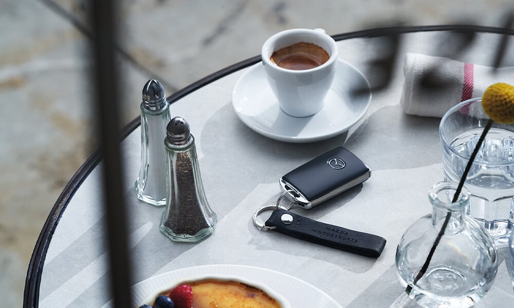 Vue de dessus d’une table avec des salières et poivrières, une pâtisserie, une tasse de café et un porte-clé Mazda.