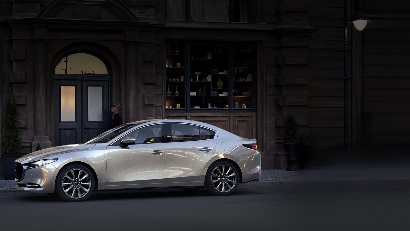 A platinum Mazda3 parked on the street.