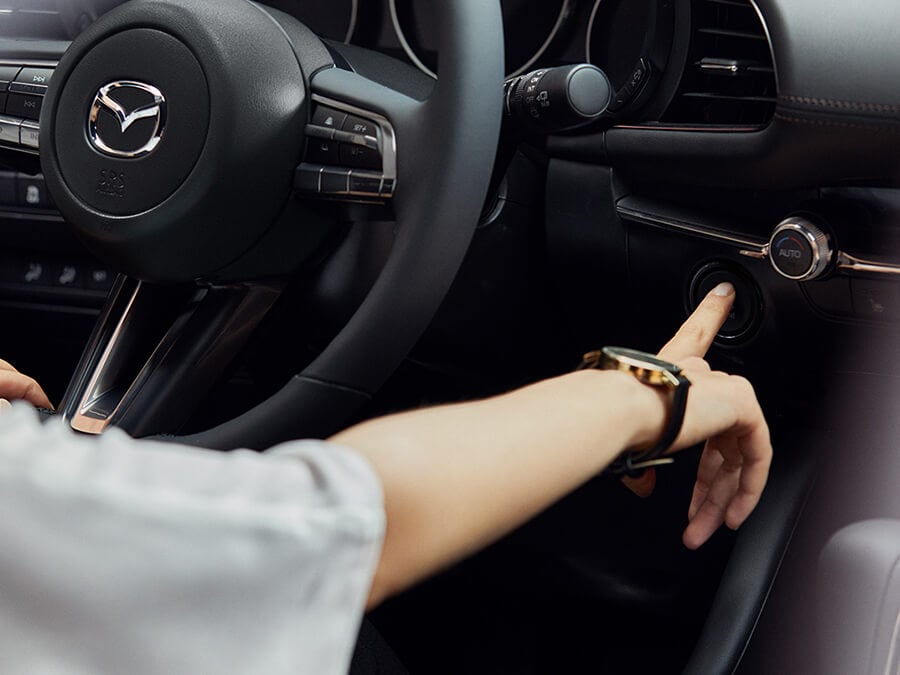 Right hand of female driver adjusts dashboard controls.