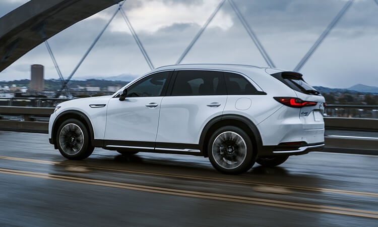 CX-90 PHEV driving across road on suspension bridge.
