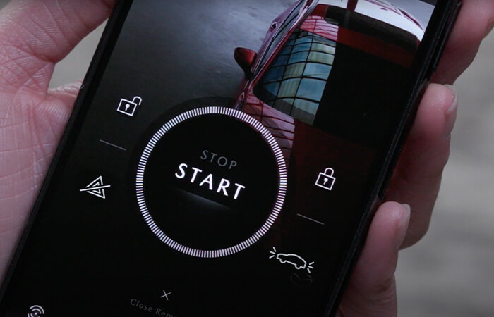 Hand holding smartphone with MyMazda app displaying start button.  
