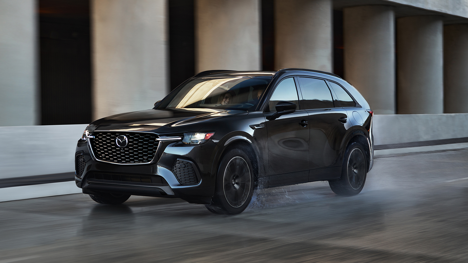 Grey Mazda6 ascending highway hill with blurred trees and hills in background 