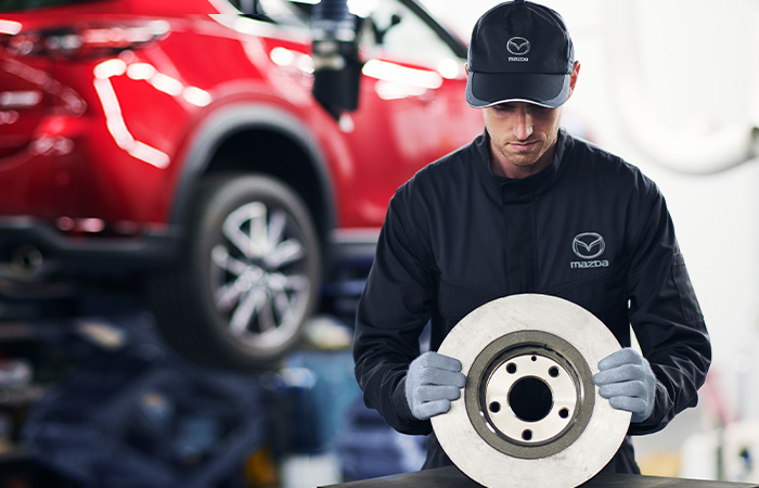  Mazda technician holding a brake rotor