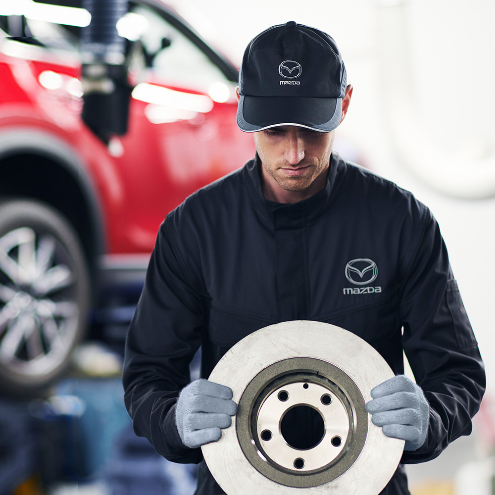  Mazda technician holding a brake rotor