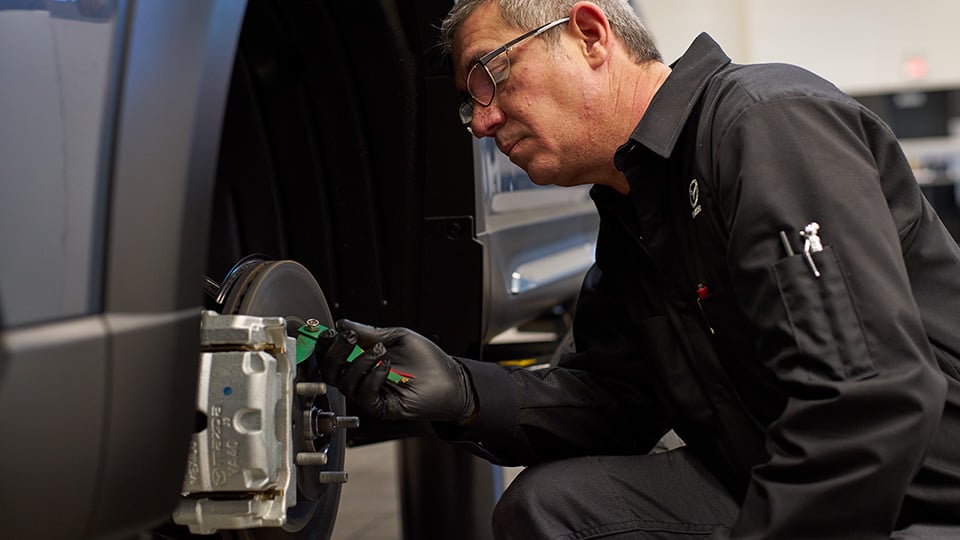 Un technicien de Mazda qui travaille sur les freins d’un véhicule