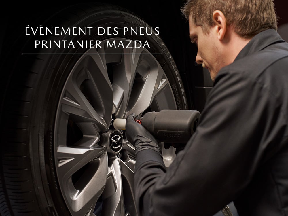 Un technicien Mazda serrant les écrous de roue sur la roue du véhicule