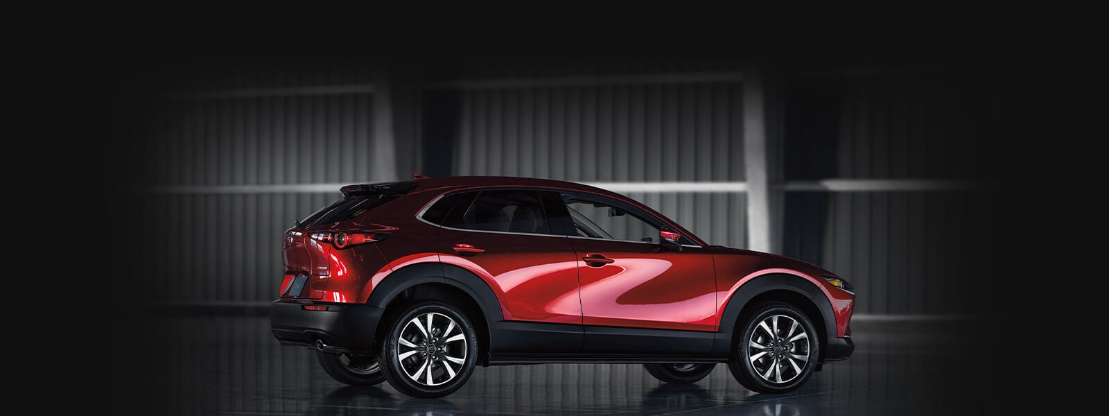 VUS Mazda rouge vibrant cristal, présenté de profil côté passager sur fond sombre