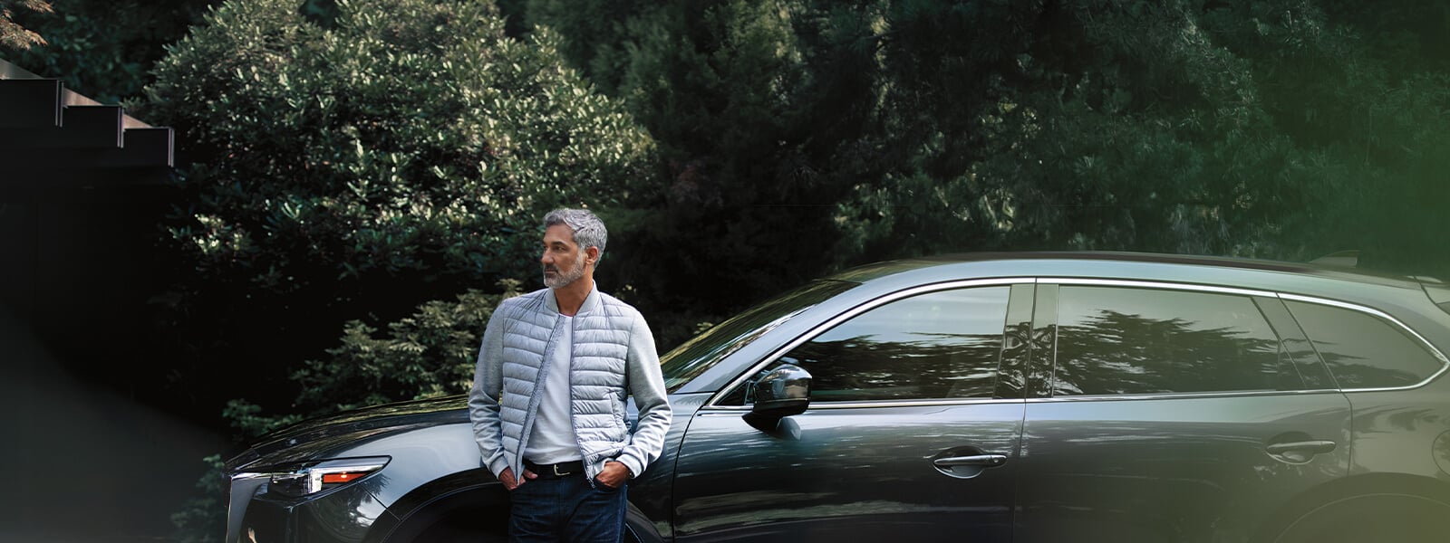 Un homme en complet gris sortant de la salle d’exposition d’un détaillant jette un regard par-dessus son épaule vers une Mazda3 Sport bleu cristal mica en démonstration