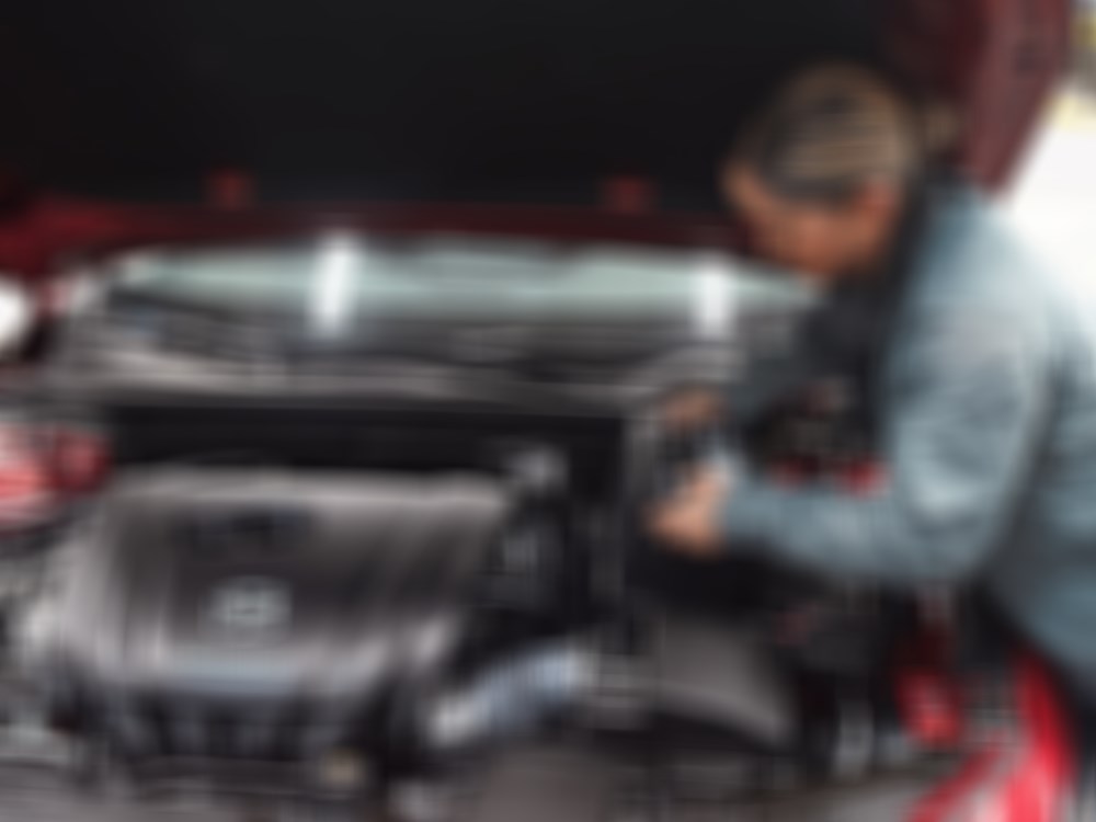 A Mazda technician working on a vehicle's engine