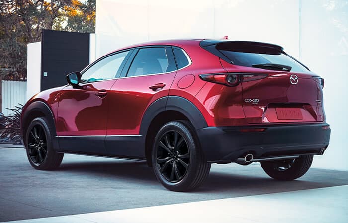Rear driver’s side view of parked Soul Red Crystal Metallic Mazda CX-30.