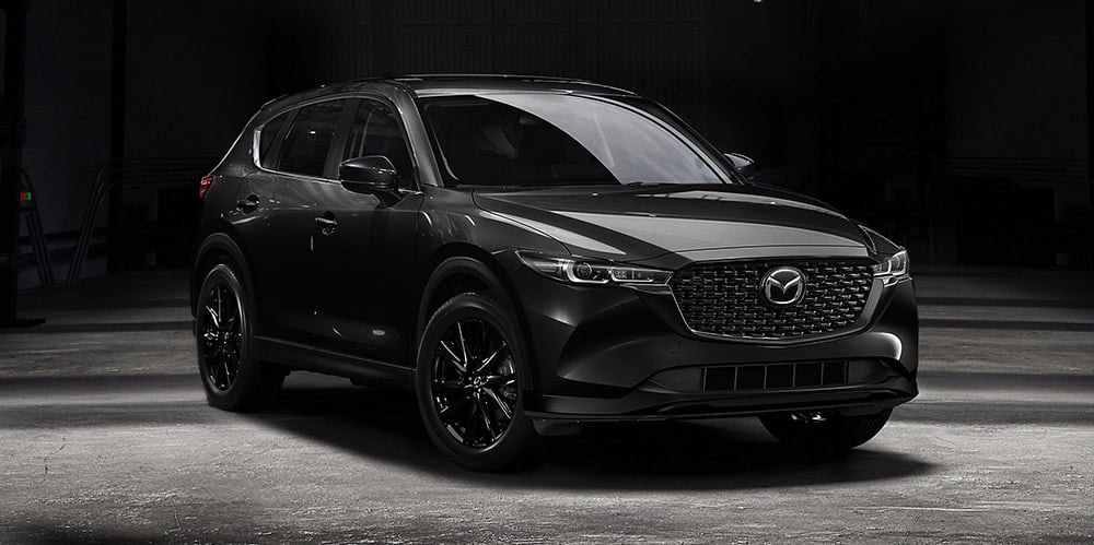 Jet Black Mica CX-5 in concrete-floored warehouse reflecting hard light from above. 