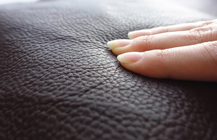 Woman’s fingers press down on leatherette surface.