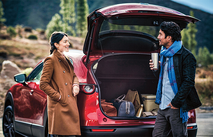 A couple chatting near the mountains by their Mazda Cx-30