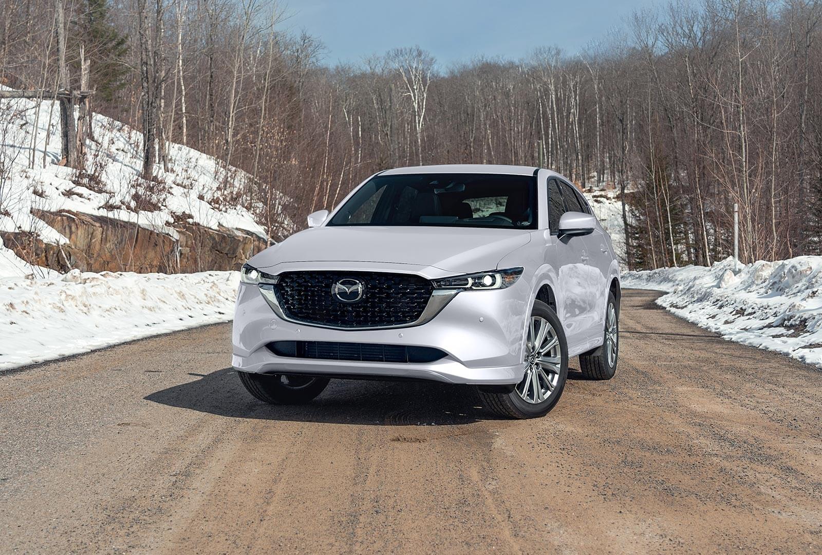 Front view of Rhodium White Metallic CX-5 parked in snowy country road. 
