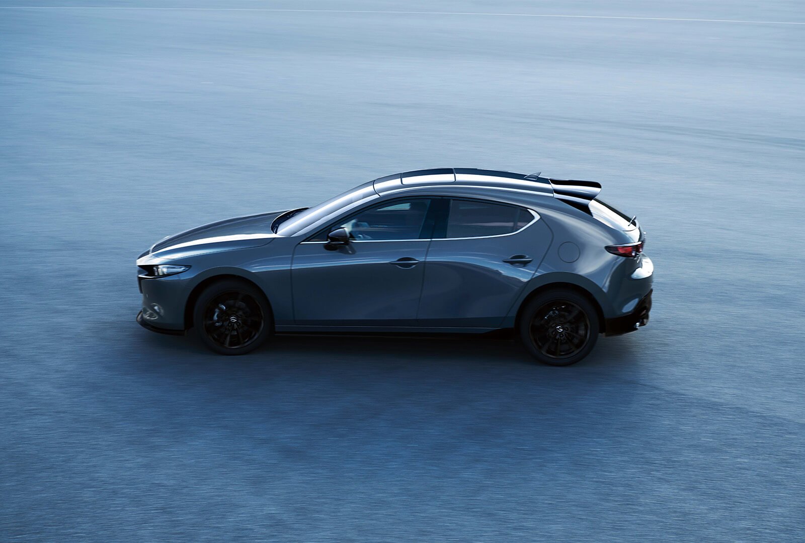 Une Mazda3 Sport d’un bleu cristal profond en mouvement.