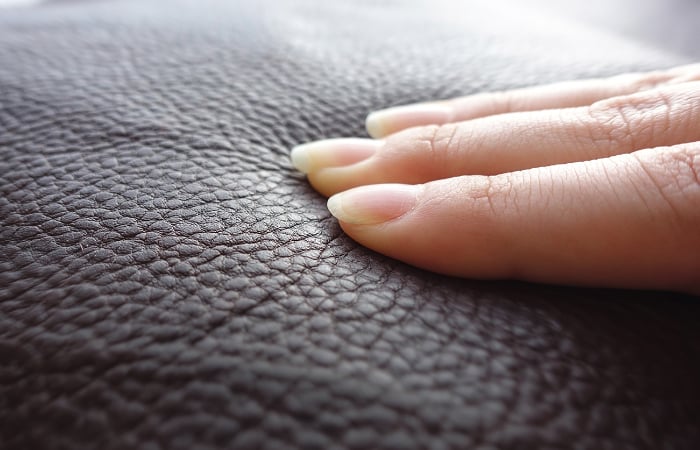 Woman’s fingers press down on leatherette surface.