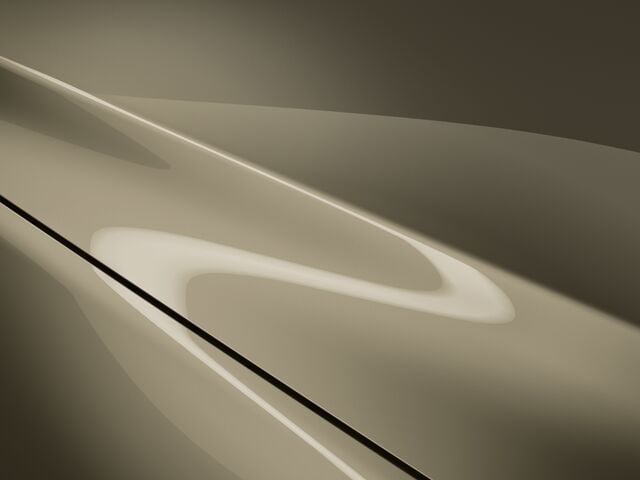 Close up on the hood of a Zircon Sand Metallic CX-5, overhead light reflects accentuating its curves.