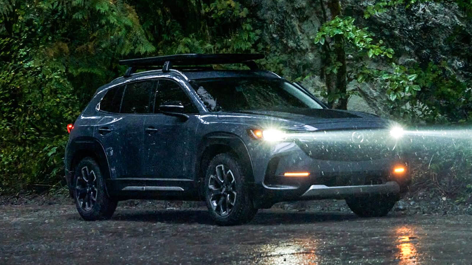 CX-50’s headlights beam into the misty, rainy air in the evening. 