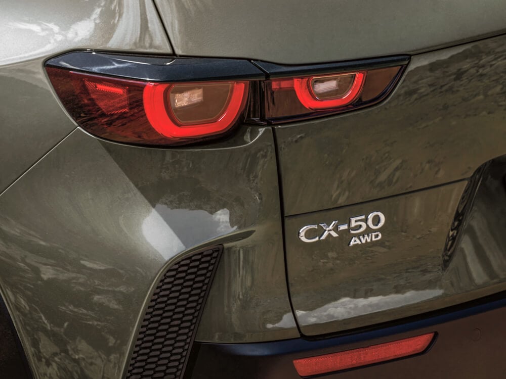 Driver’s side rear shot of lit taillight and CX-50 AWD badge.  