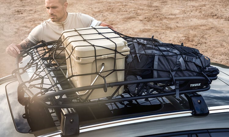Man secures cargo with net on the CX-50’s roof rack. 