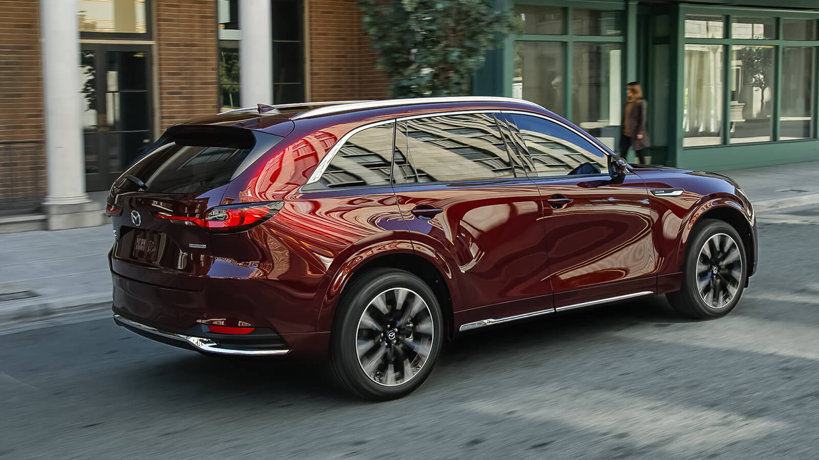 Artisan Red CX-90 passes main street storefronts on city street.  