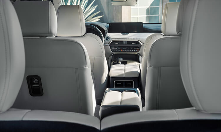 View from behind the third row up the middle of the White Nappa leather interior of the CX-90 and into the front seats. 