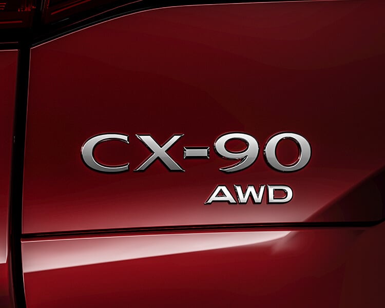 Closeup of CX-90 AWD vehicle nameplate badge.