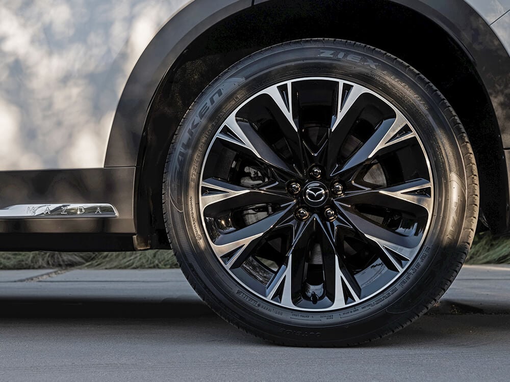 Closeup of 21-inch alloy wheel with machined spokes, polished finish and dark painted pockets. 