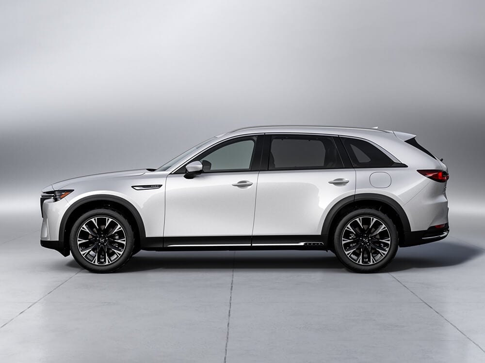 Driver’s side profile of Arctic White CX-90 on grey background.