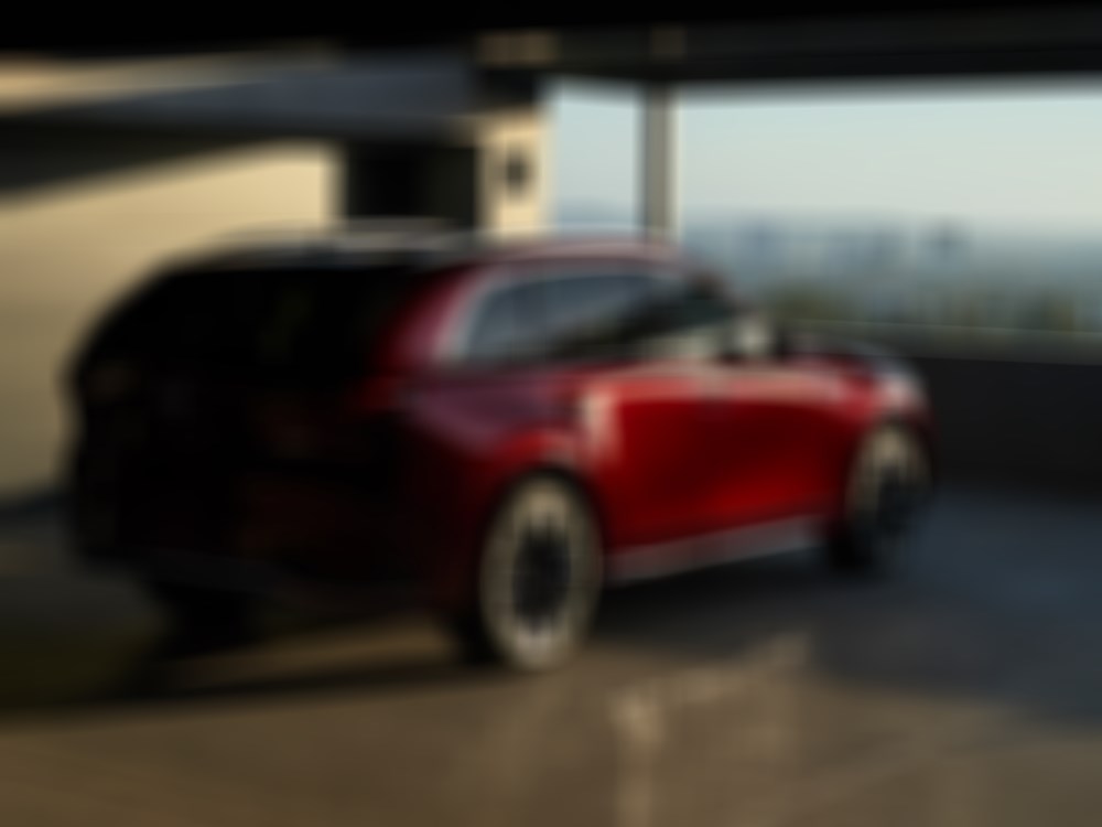 Artisan Red Cx-90 parked in parking garage overlooks a cityscape at sunset.