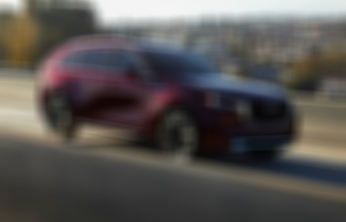 Artisan Red CX-90 driving down concrete highway overpass.