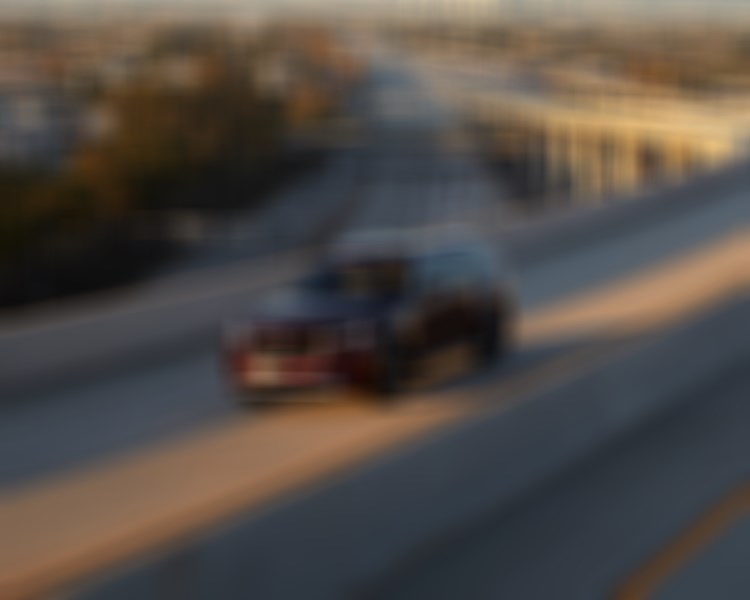 Artisan Red CX-90 drives along concrete highway overpass at sundown.