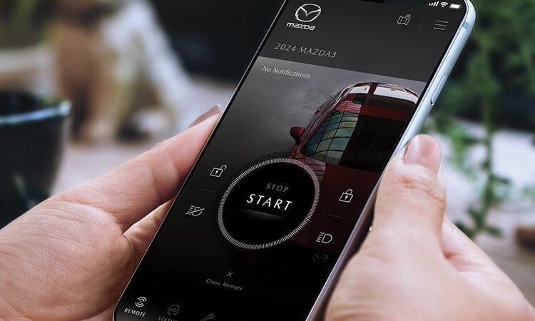 Smartphone with MyMazda app on vehicle start screen.