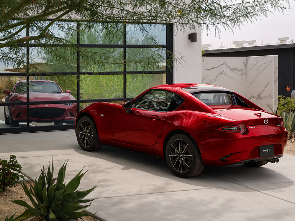 Soul Red Crystal Metallic MX-5 RF parked in driveway, reflected in mirrored garage door. 