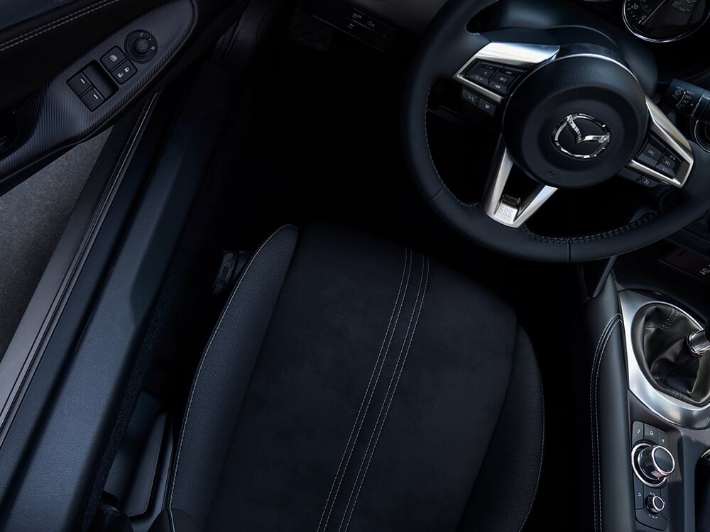 Top down view from inside the MX-5's driver’s seat shows the seat’s material, stitching and steering wheel.