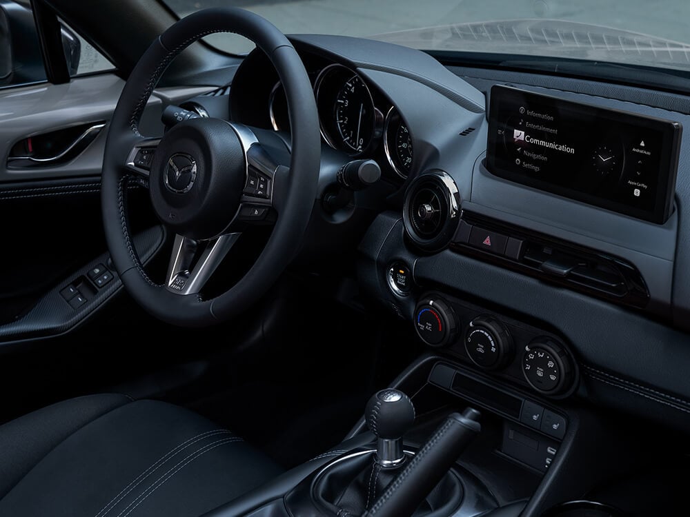 View inside the MX-5 from the passenger’s seat shows centre console controls and touchscreen display.