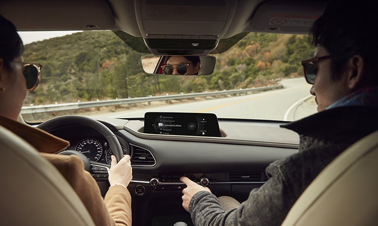 CX-30 driving on mountain road, view from inside, backseat looking forward at the driver and passenger in front seats.