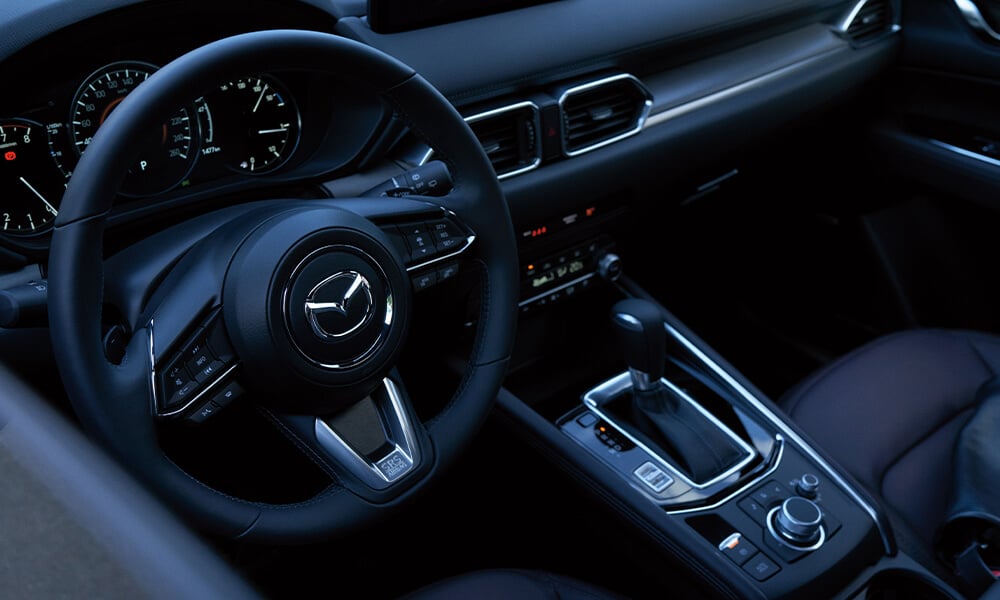 Top-down view of Mazda CX-5 driver’s side showing steering wheel, gear shifter, and control console.