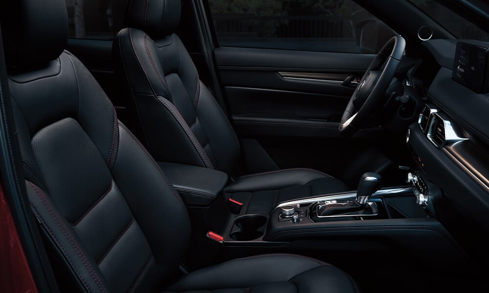 Interior of Mazda CX-5, passenger’s side view showing seats, steering wheel, and control panel.