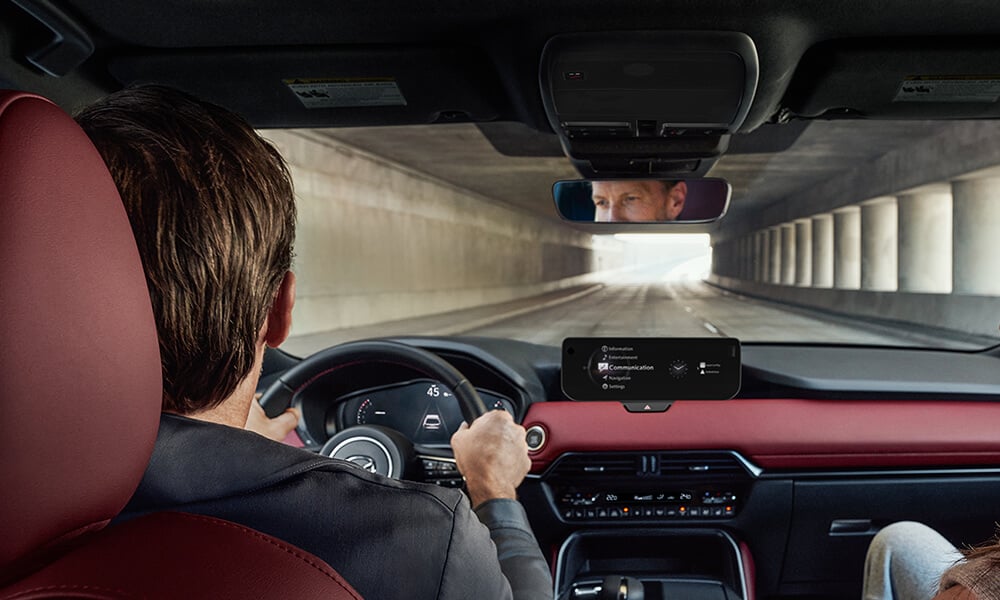 Shot from the second row inside the CX-70, the driver and passenger focus on the road ahead. 