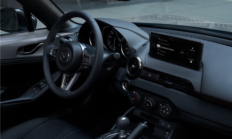 A driver in sunglasses uses their right hand to adjust settings on the dashboard controls.