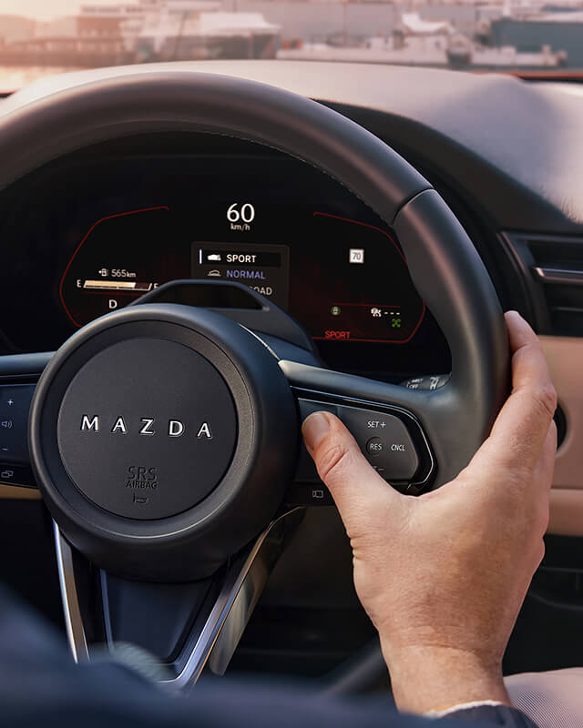 Une main activant une commande au volant du Mazda CX-5.