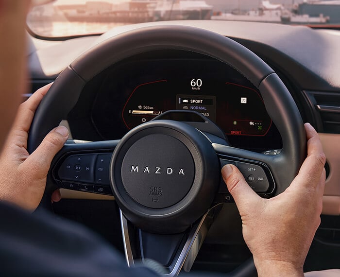Hand activating a steering wheel control in the Mazda CX-5.