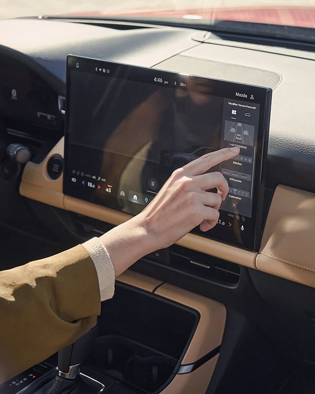 Une main utilisant l’écran tactile central du Mazda CX-5.