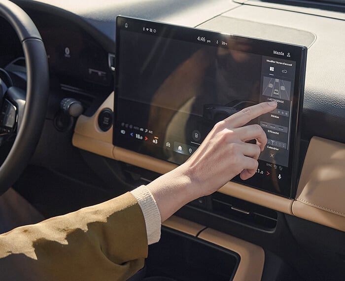 Une main utilisant l’écran tactile central du Mazda CX-5.