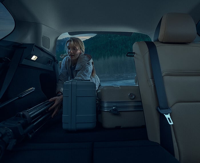 Interior view of a woman driving a Mazda CX-5 with blue ambient lighting.