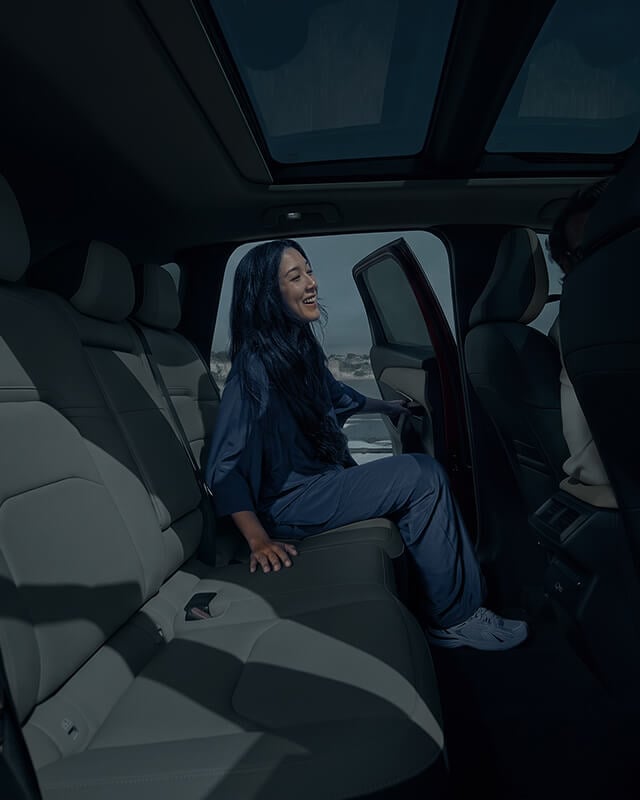 Interior view of a Mazda CX-5 with a woman entering the rear seat from the opposite side.