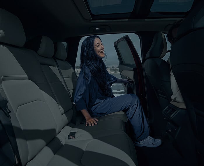 Interior view of a Mazda CX-5 with a woman entering the rear seat from the opposite side.